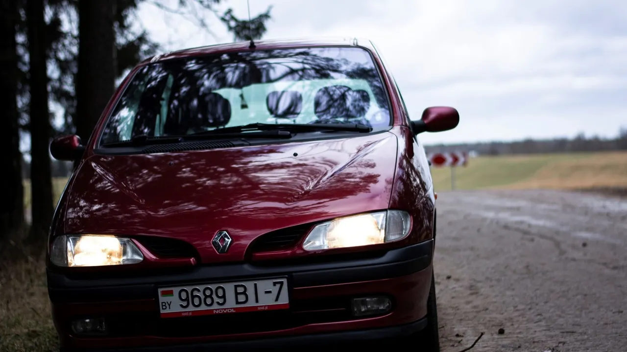Renault Scenic 3 gris stationné en ville, vue trois quarts avant, avec Grand Scénic en arrière-plan